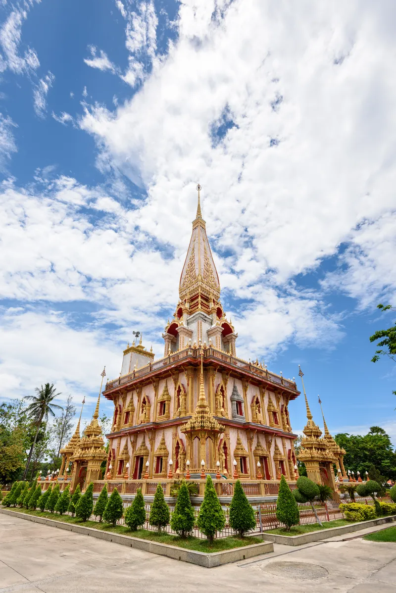Phuket temples: golden stupas of Wat Chalong and Big Buddha statue against tropical greenery