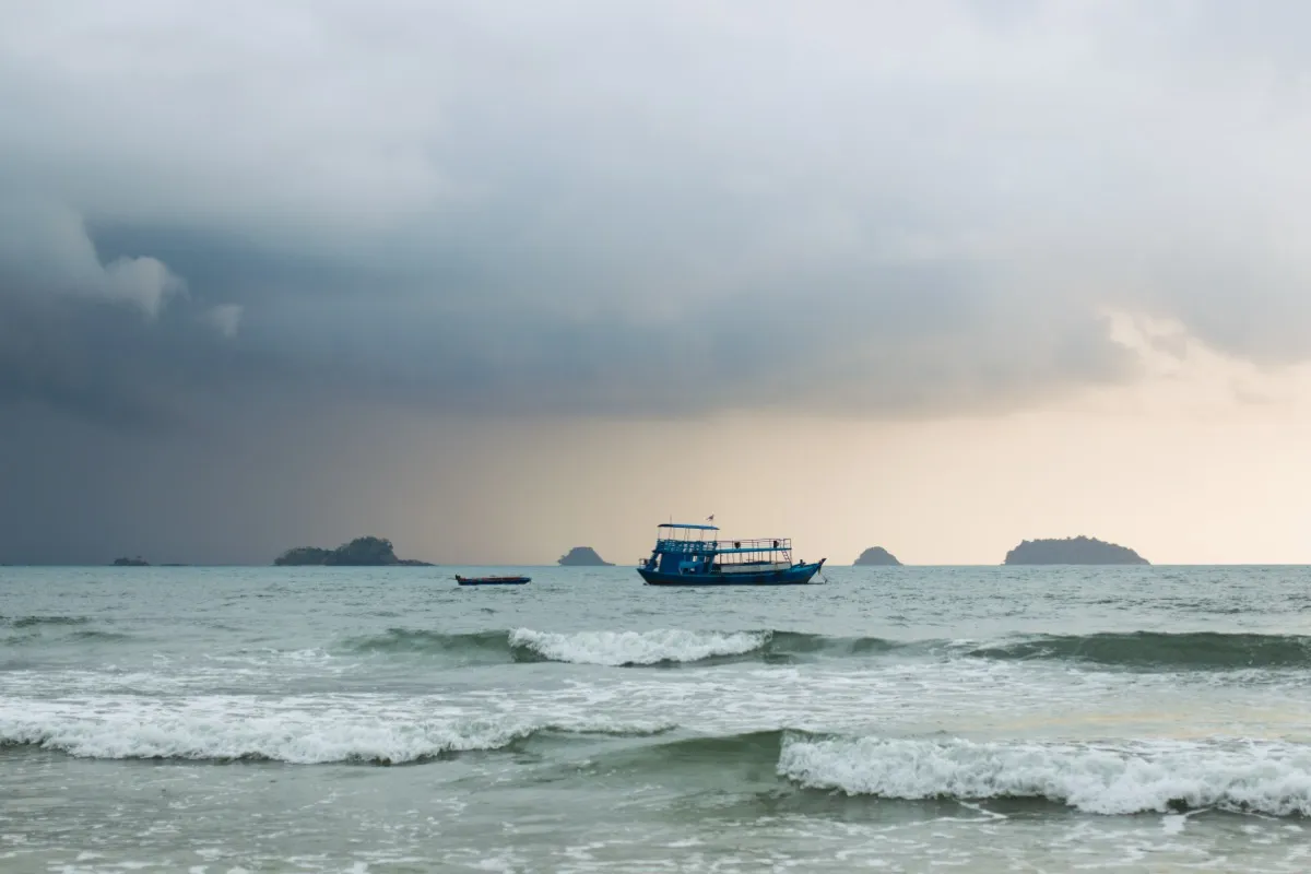 Phuket in September — tropical rain over the sea and green palm trees